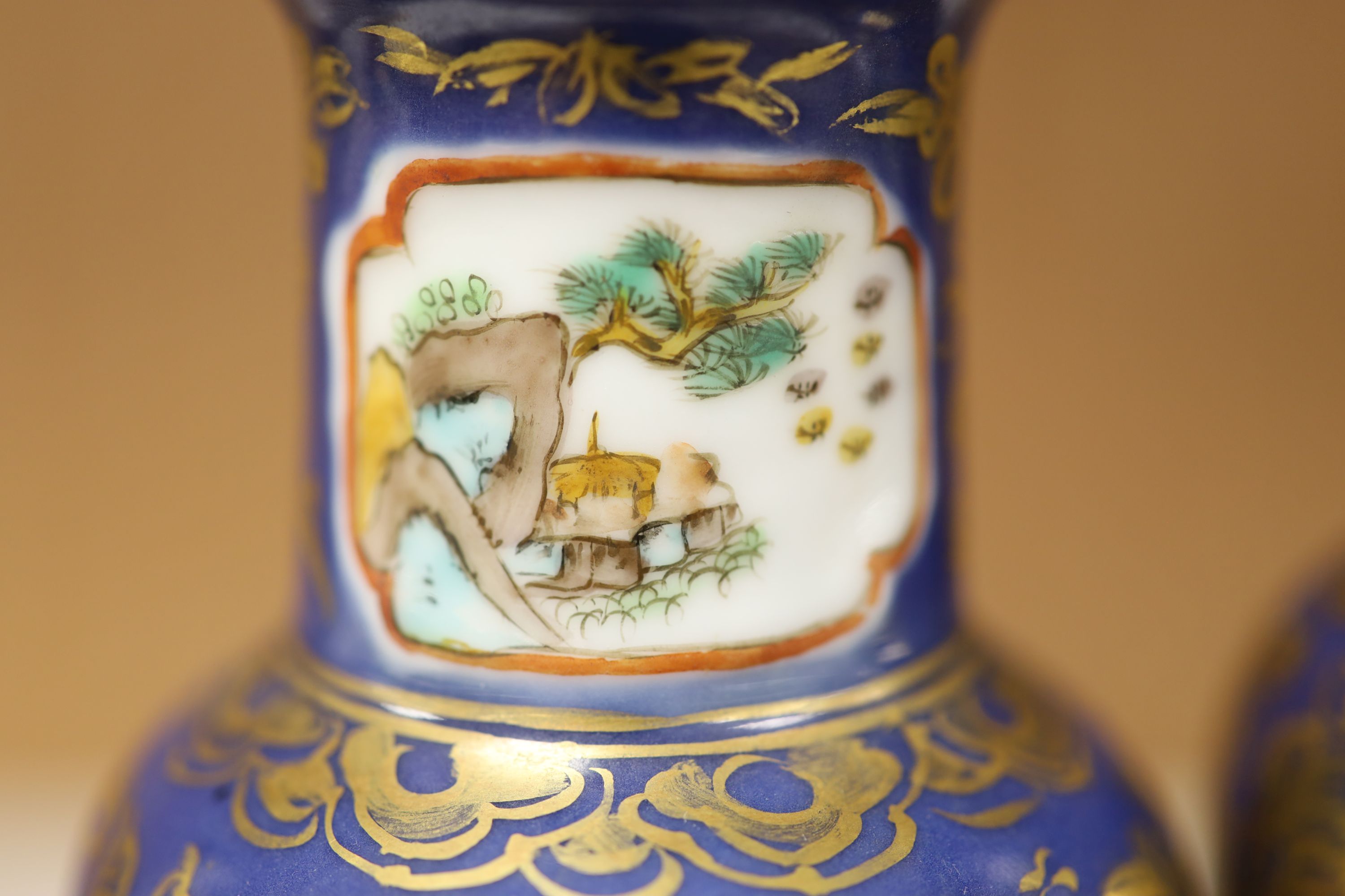 A pair of Chinese Kangxi style blue-ground vases, late 19th century decorated with panels of warriors and heightened in gilt, on carved hardwood stands, height 18cm excluding stand